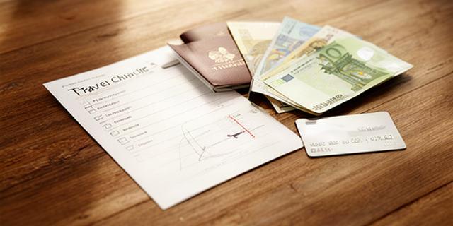 Ingevulde reisgeldchecklist naast paspoort, eurobiljetten, dollars en creditcard op een houten tafel